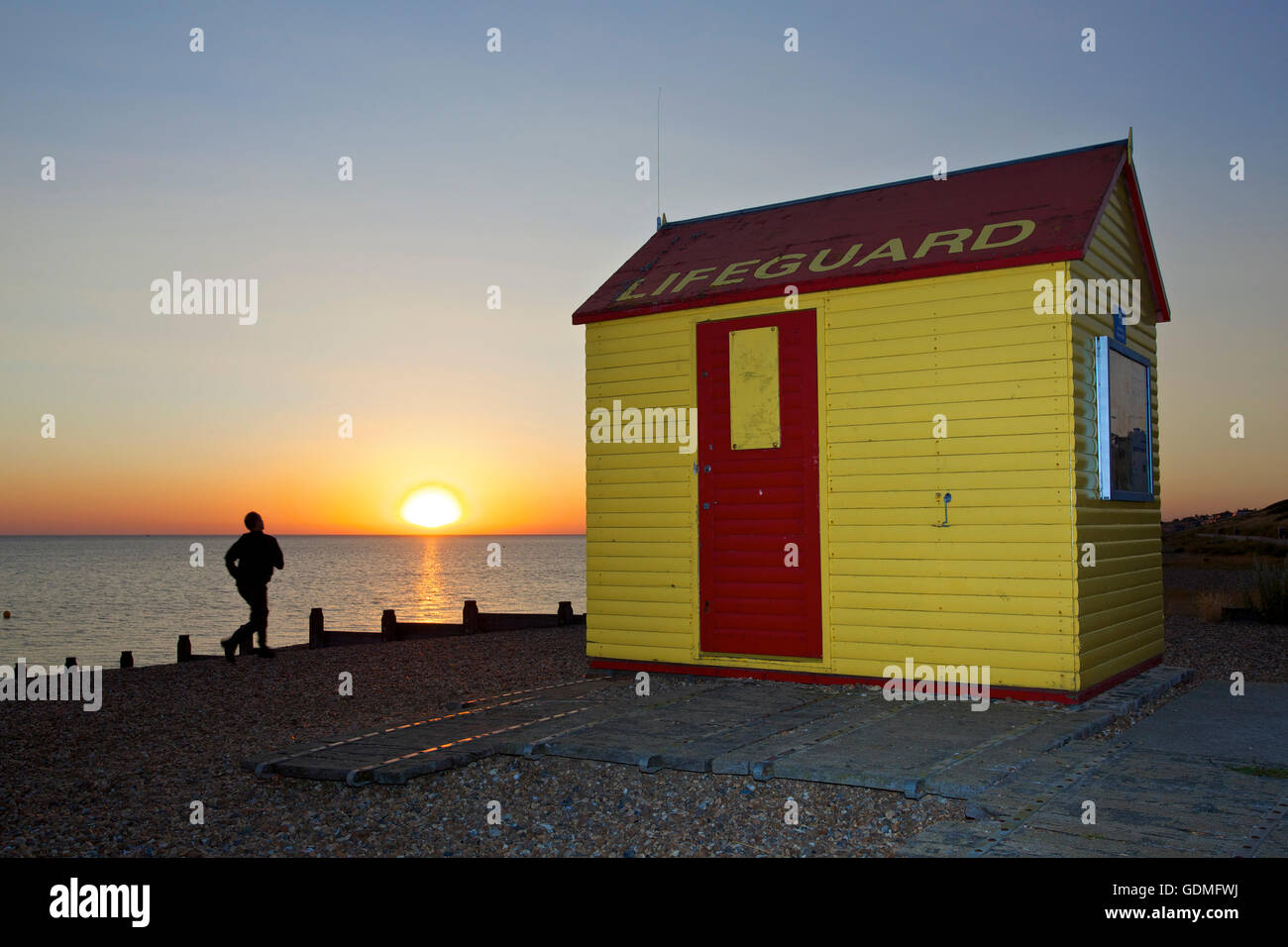 Tankerton, Kent, UK 20th July 2016: UK Weather. The sun rises into a hazy but cloudless sky as a jogger runs along the beach at Tankerton near Whitstable in Kent after a night where temperatures did not fall below 22°C. The weather is set to cool down with showers forecast for Thursday Credit:  Alan Payton/Alamy Live News Stock Photo