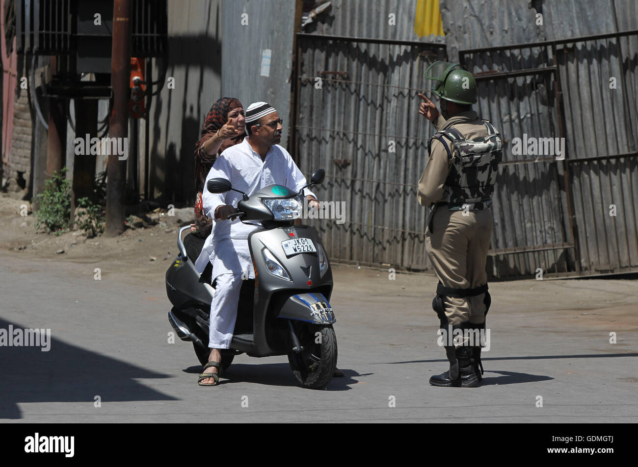 Srinagar, Indian-controlled Kashmir. 19th July, 2016. An Indian paramilitary trooper stops a scooterist and a woman during a curfew in Srinagar, summer capital of Indian-controlled Kashmir, July 19, 2016. Protests have been held in Kashmir since July 9 over the killing of Burhan Wani, a top figure in the pro-independence Hizbul Mujahideen group. Credit:  Javed Dar/Xinhua/Alamy Live News Stock Photo