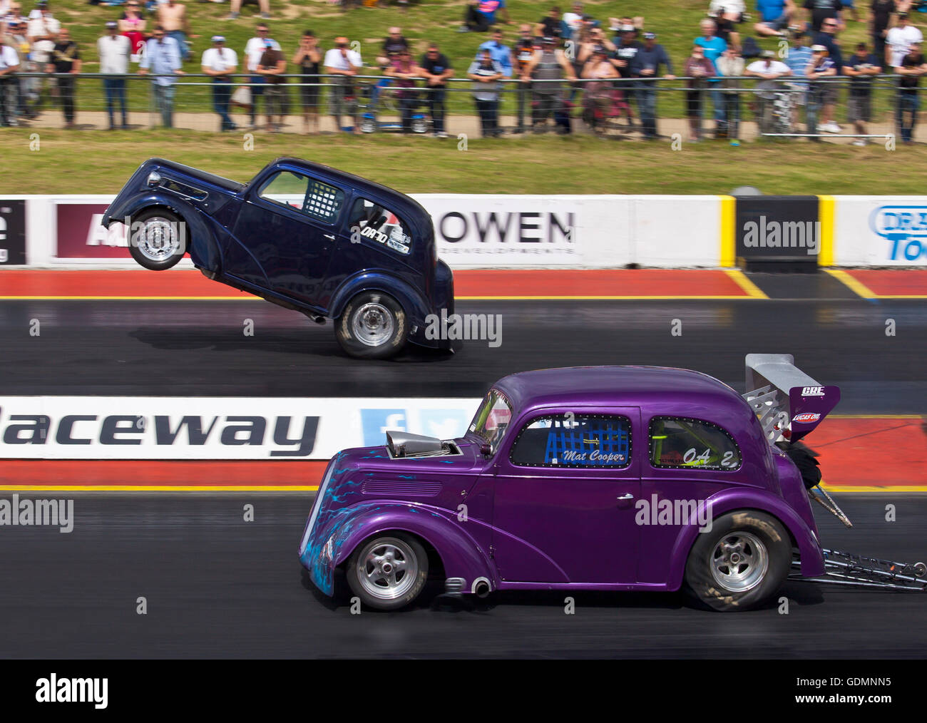 Dragstalgia event at Santa Pod. Mat Cooper driving his Outlaw Anglia nearside and Mark Bracking pulling a wheelie far side. Stock Photo