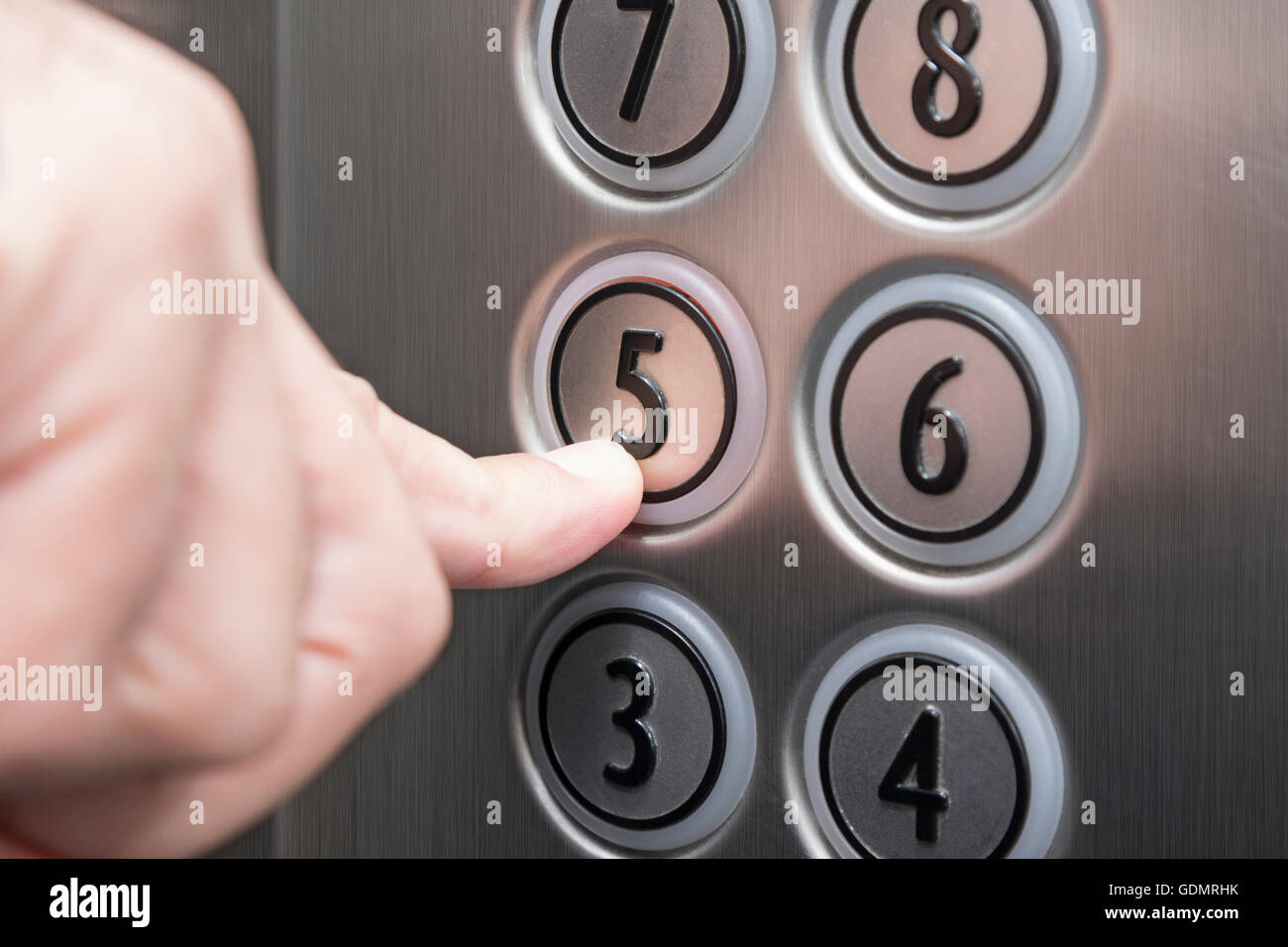Forefinger pressing the fifth floor button in the elevator Stock Photo