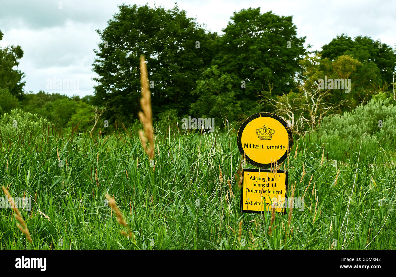 Yellow sign in danish militaries exercise area - round sign saying 'Military field' - square sign saying 'Entrance only accordin Stock Photo