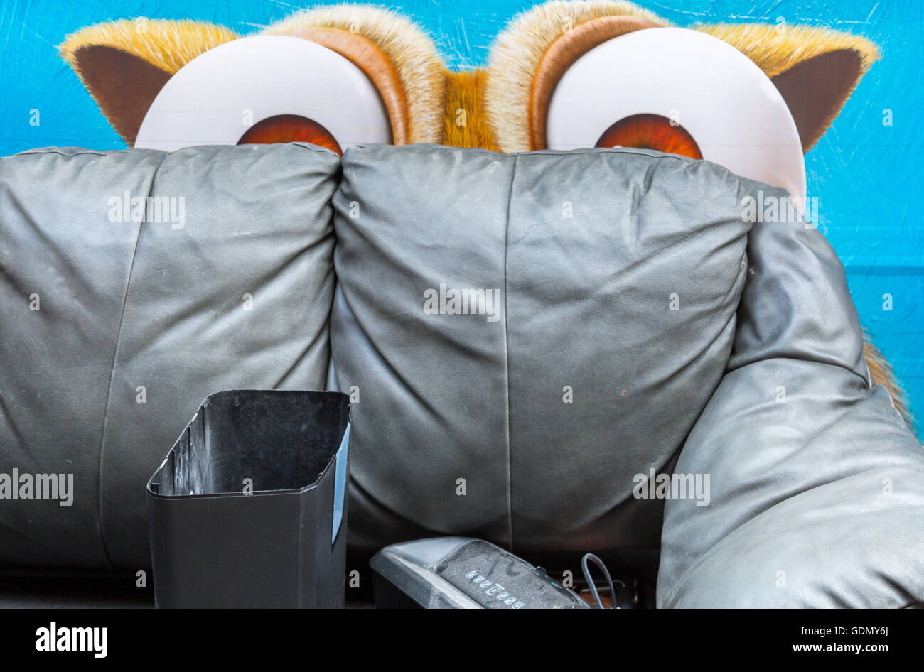 cartoon eyes peering over a old thrown out couch on a NYC sidewalk Stock Photo