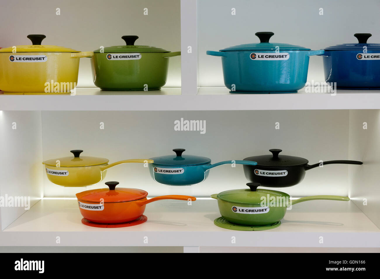 Colorful Le Creuset enamelled cast iron cookware on white shelving in a Le Creuset boutique Stock Photo