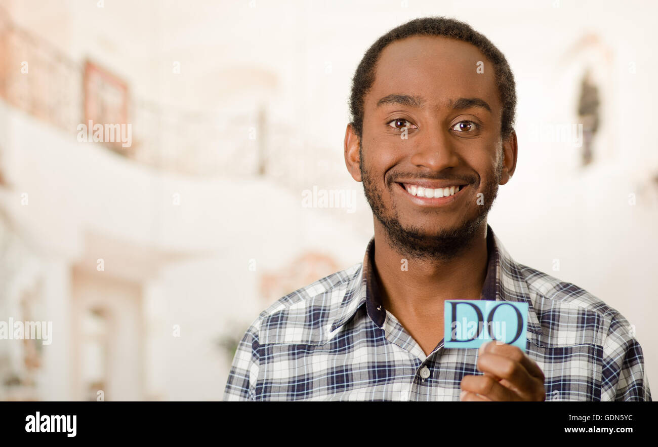 Headshot handsome man holding up small letters spelling the word do and ...