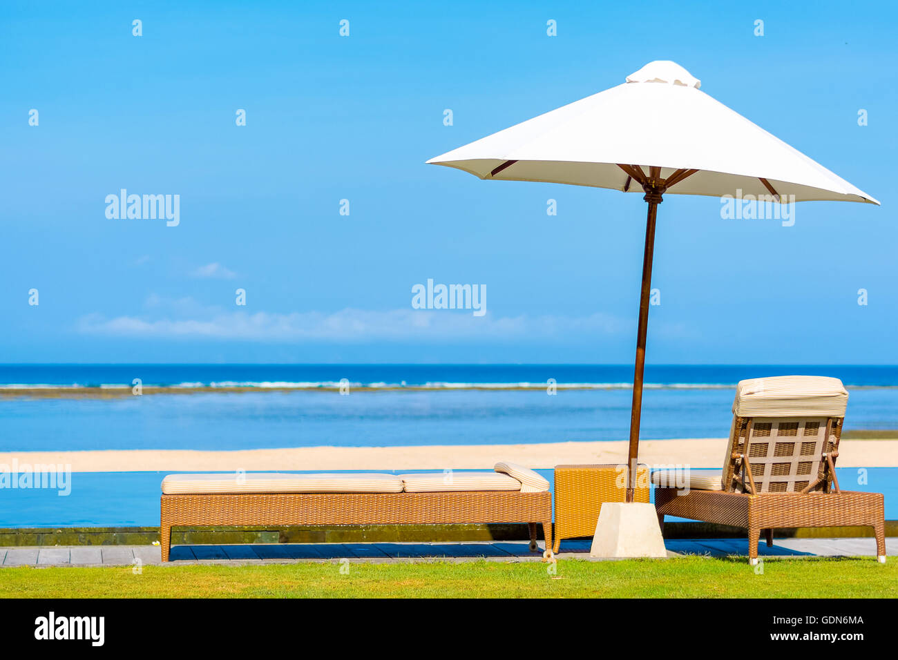 Sun umbrella & daybeds overlooking beautiful tropical beach in Bali on a perfect sunny day. Stock Photo