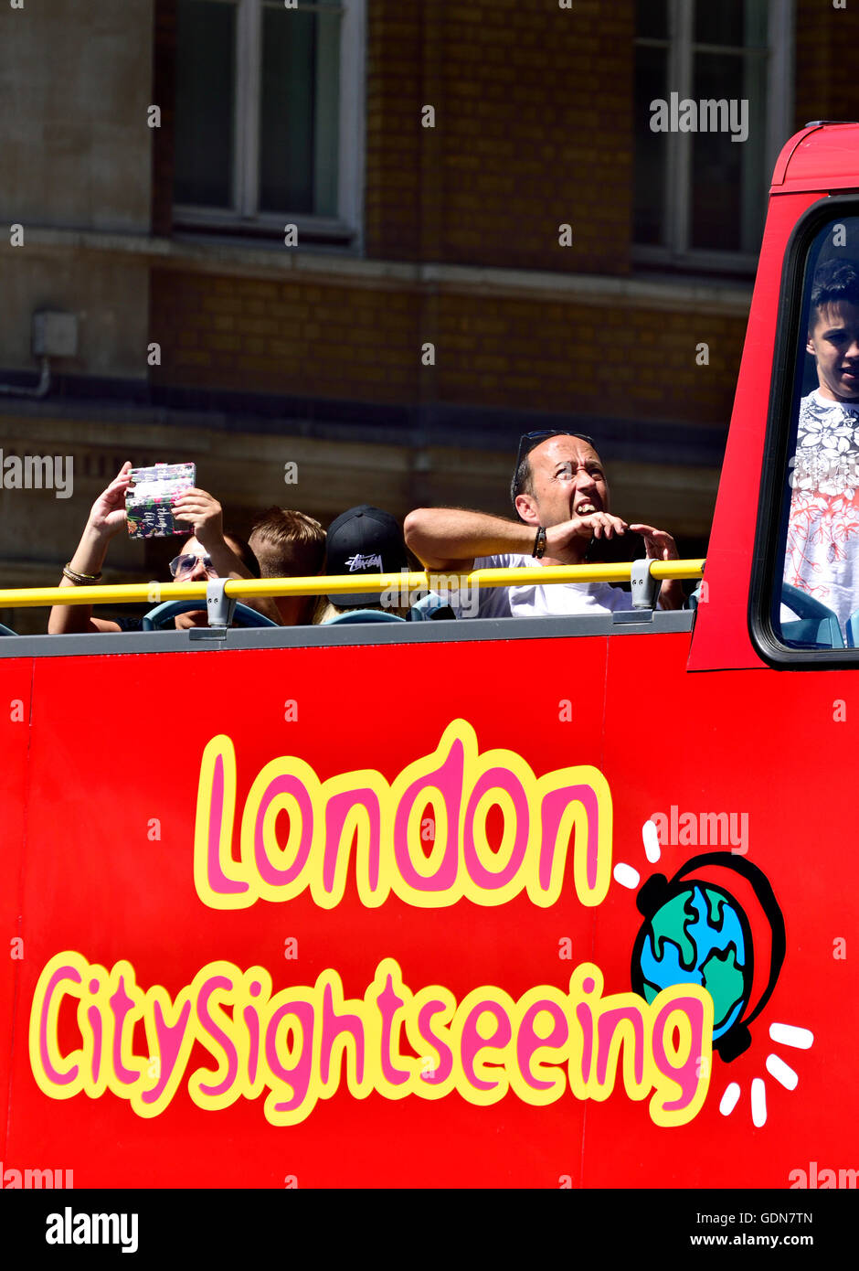 London, England, UK. Tourists on the top floor of an open-top sightseeing bus Stock Photo