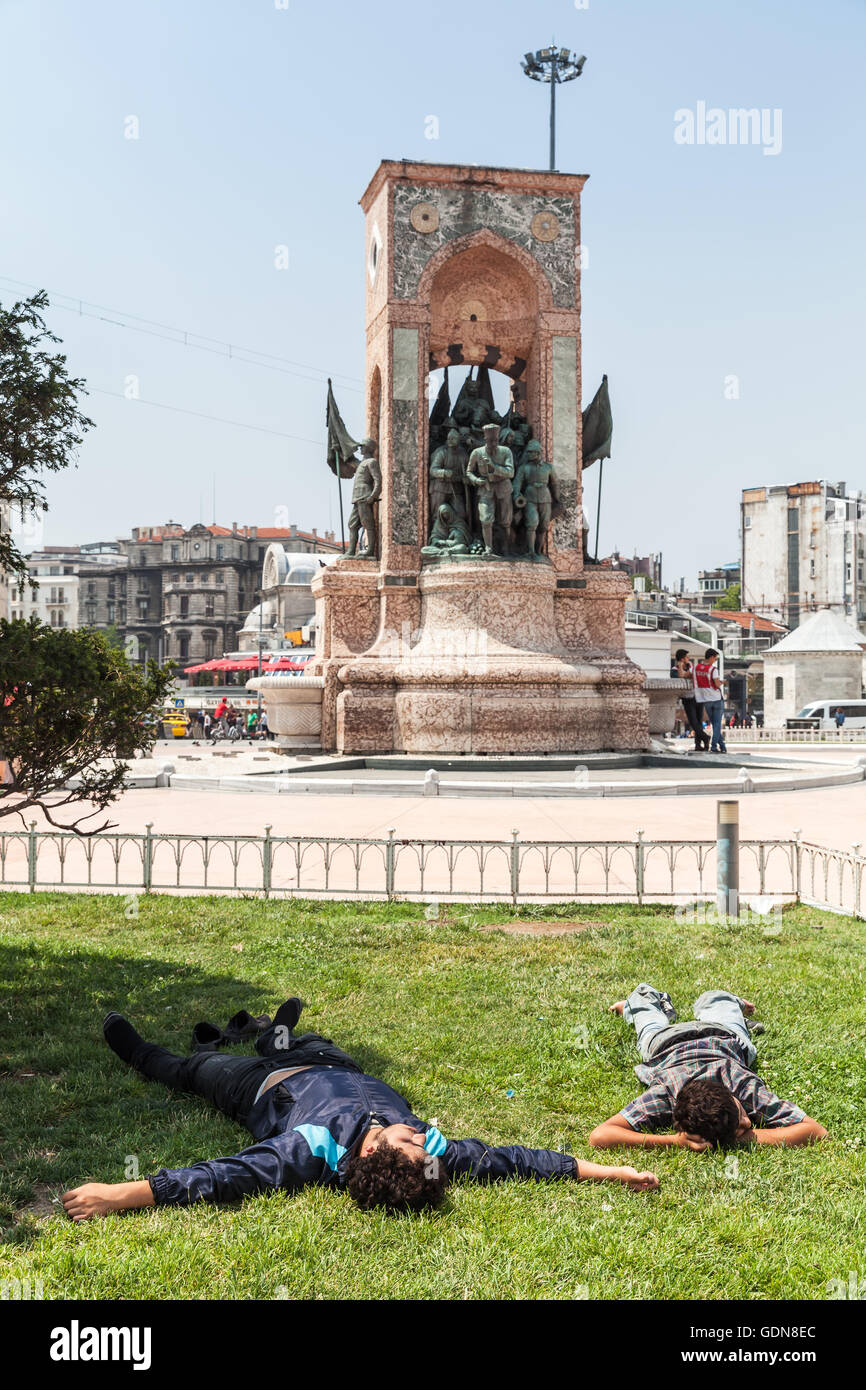 Istanbul, Turkey - July 1, 2016: Young homeless men sleep on Taksim square near the Republic Monument Stock Photo
