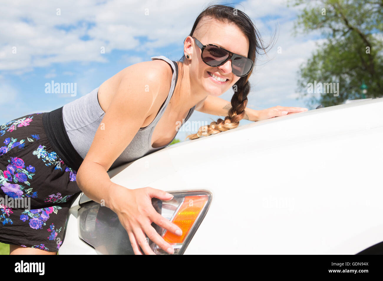 Cheerful young female driver hugging her new car Stock Photo