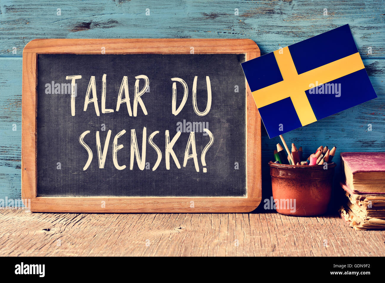 a chalkboard with the question talar du svenska?, do you speak Swedish? written in Swedish, a pot with pencils, some books and t Stock Photo