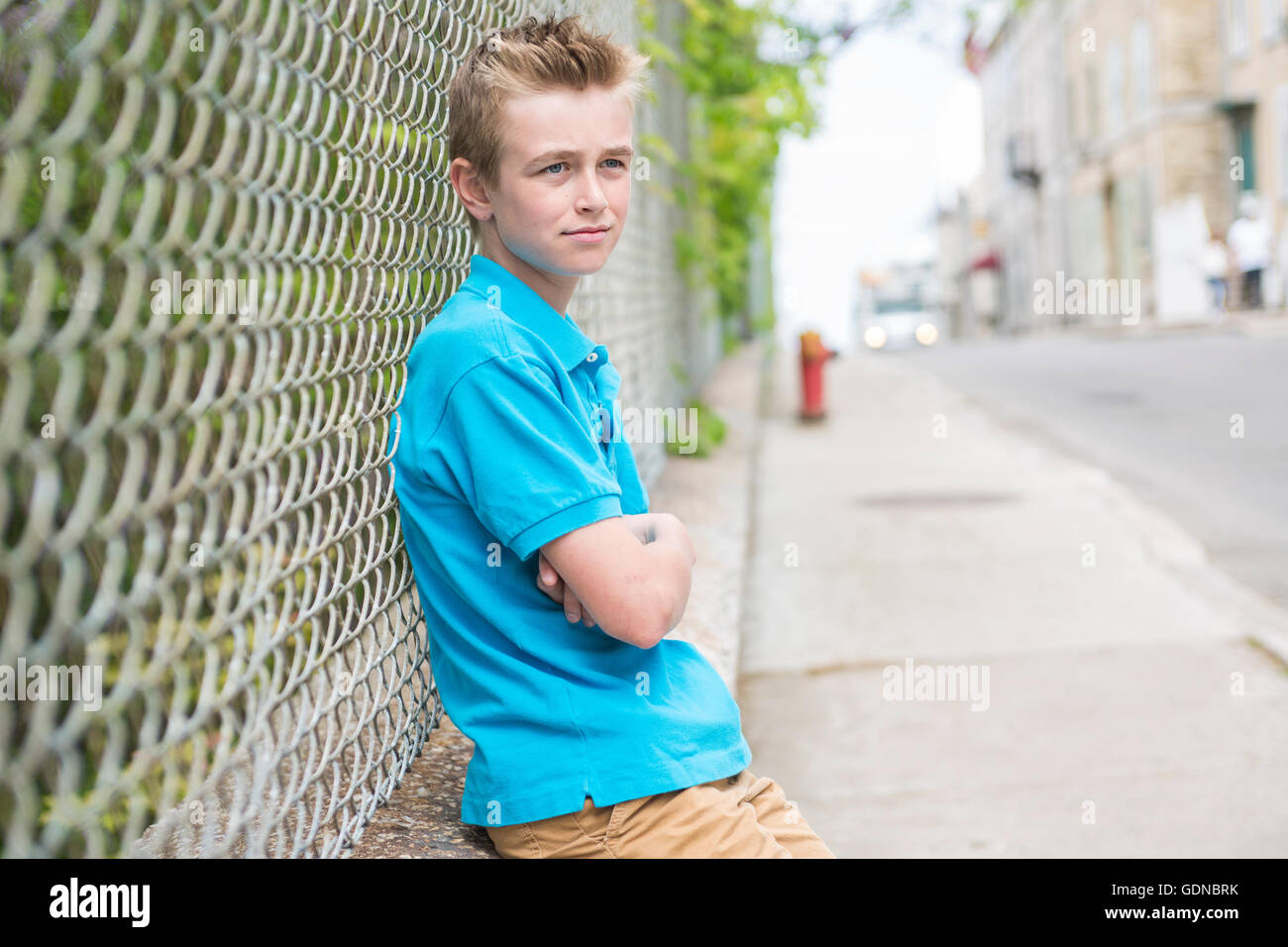 young teen boy looking out of a fence Stock Photo