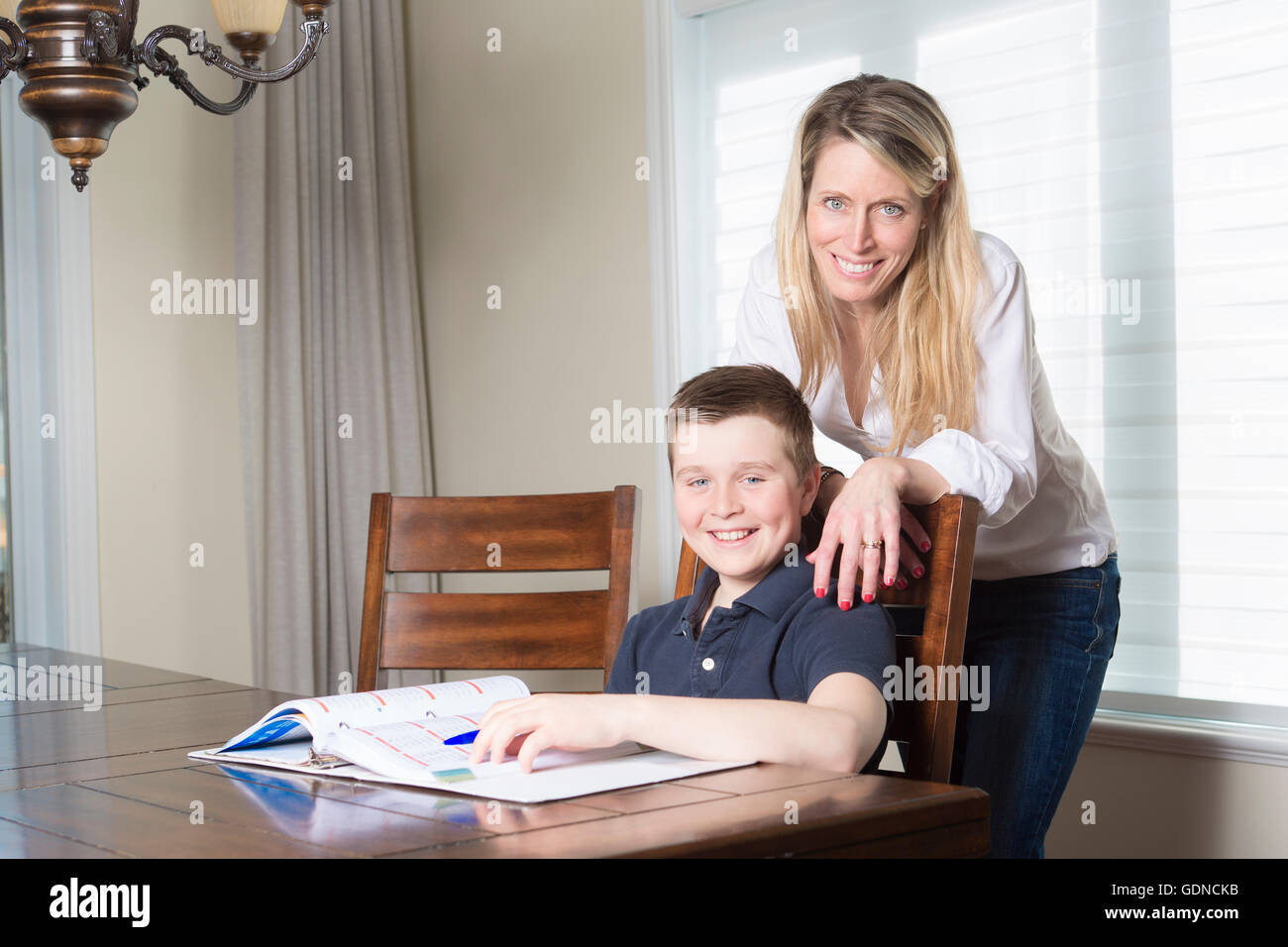 mother at a table home helping her small son with his homework Stock ...