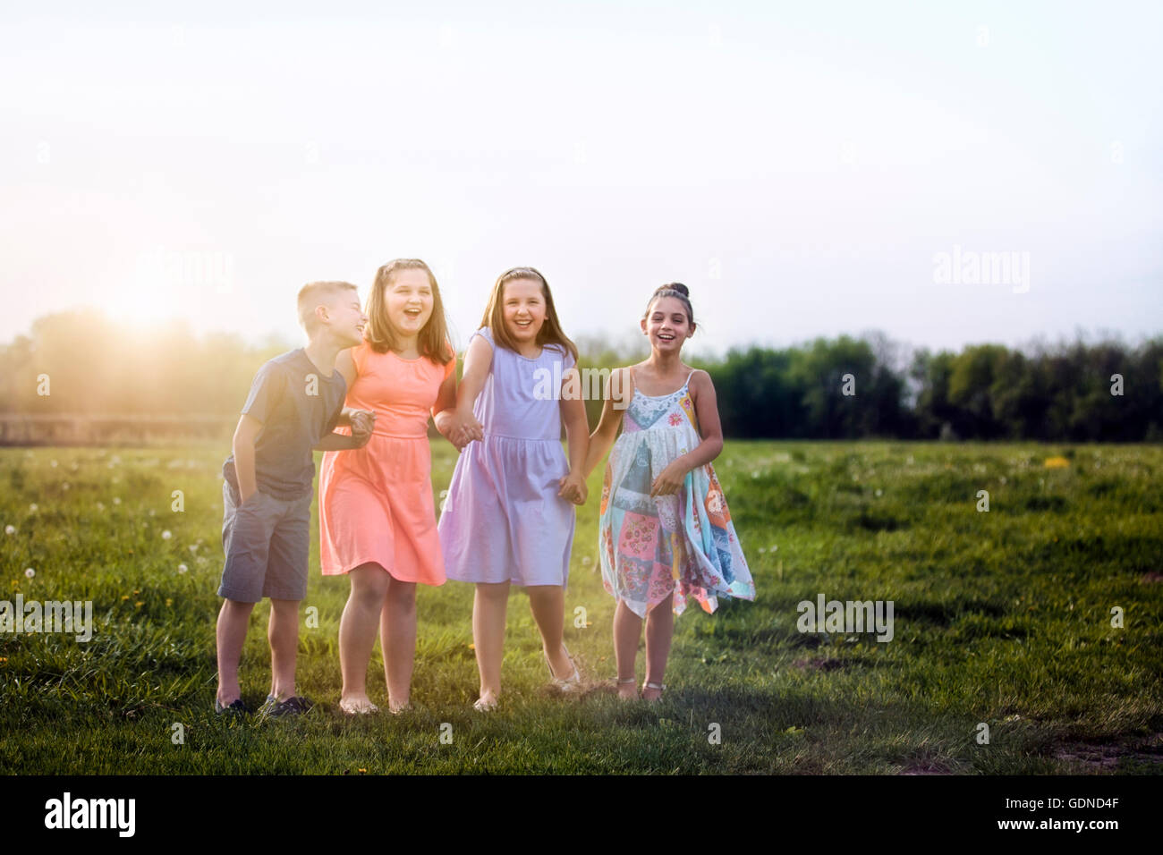 Children in field holding hands laughing Stock Photo