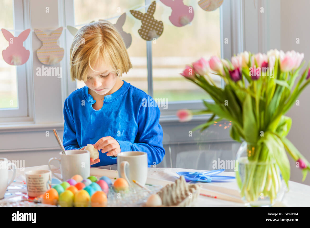 Boy at table decorating eggs for Easter Stock Photo