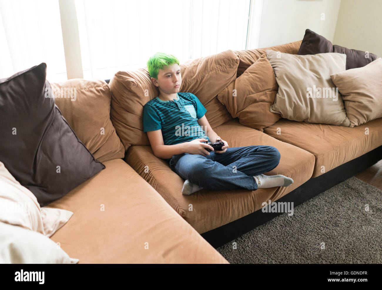 Boy playing video game on sofa Stock Photo