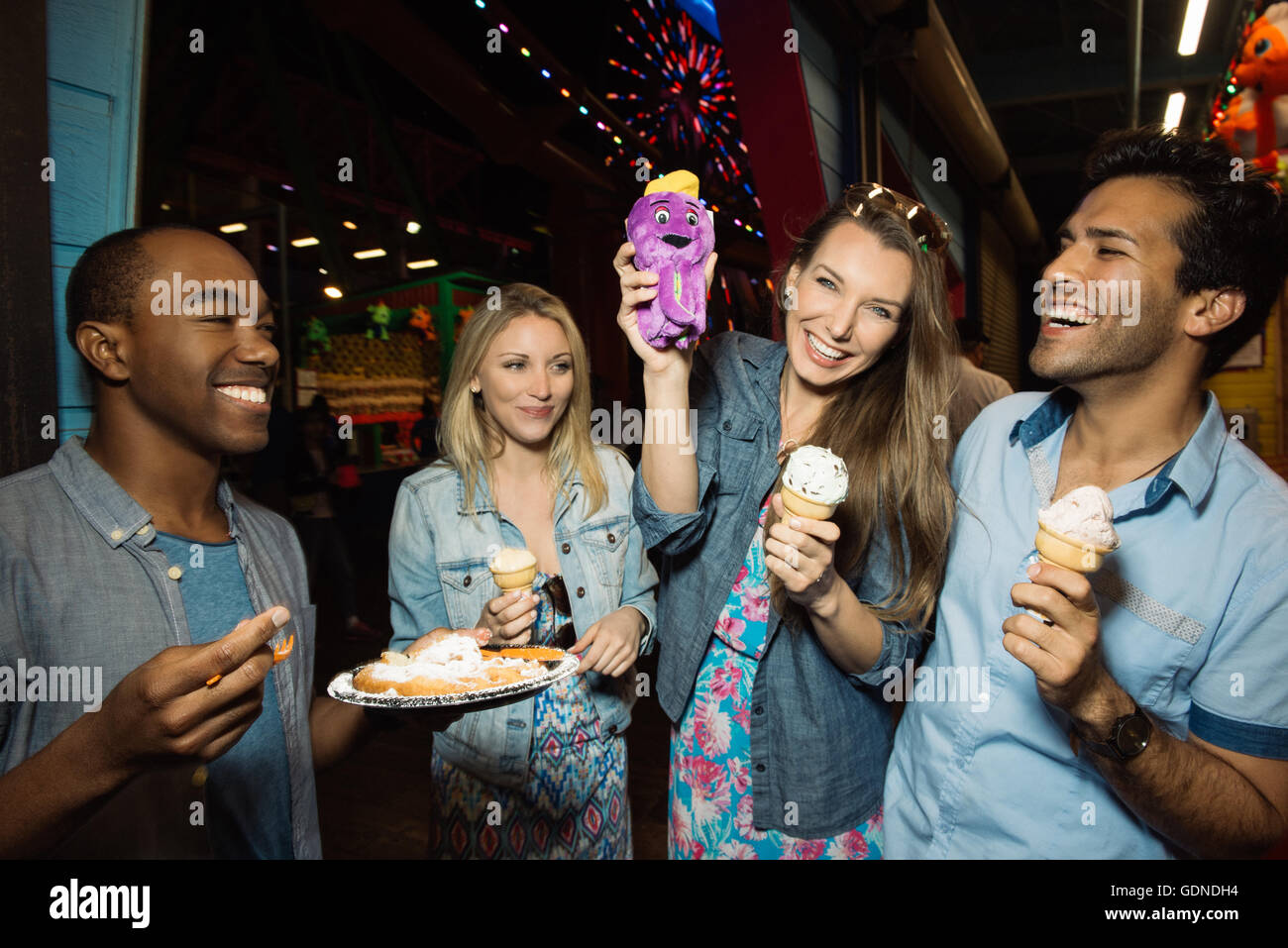 Adult friends eating ice creams in amusement park at night, Santa