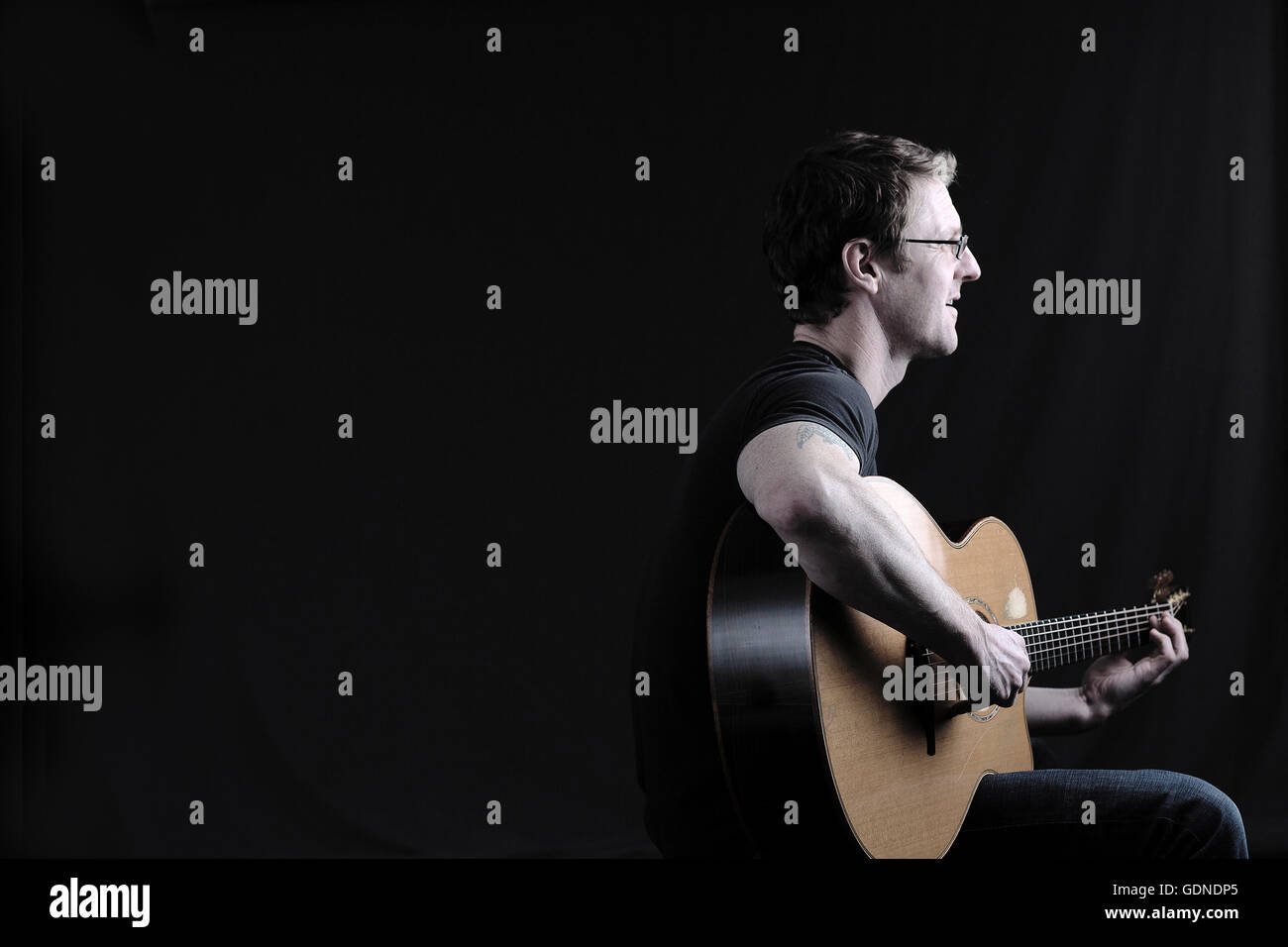 Low key shot of mid adult man playing acoustic guitar Stock Photo