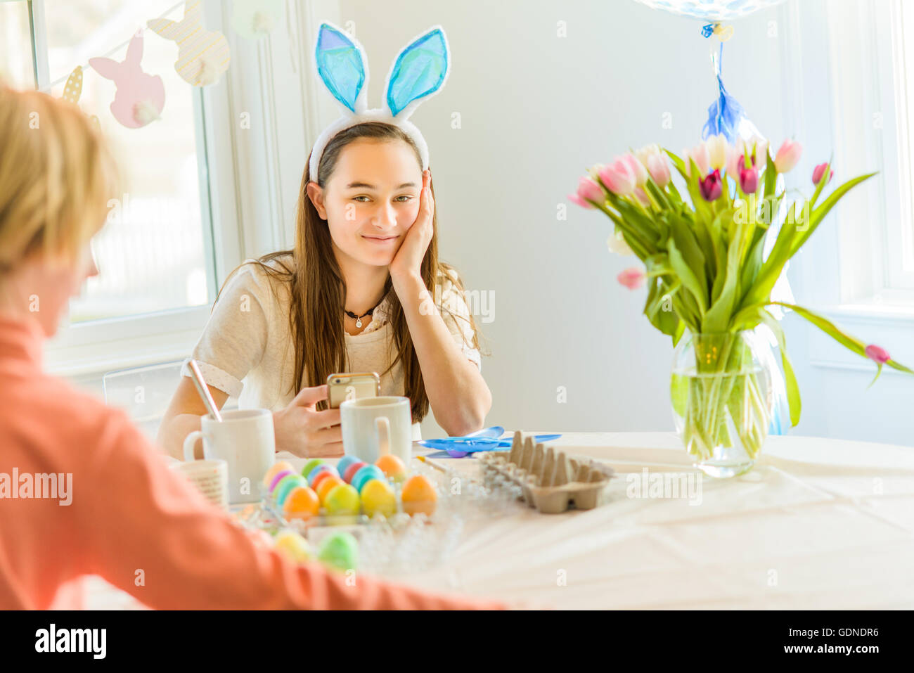 Teenage girl and brother at table dyeing hard boiled eggs for Easter Stock Photo