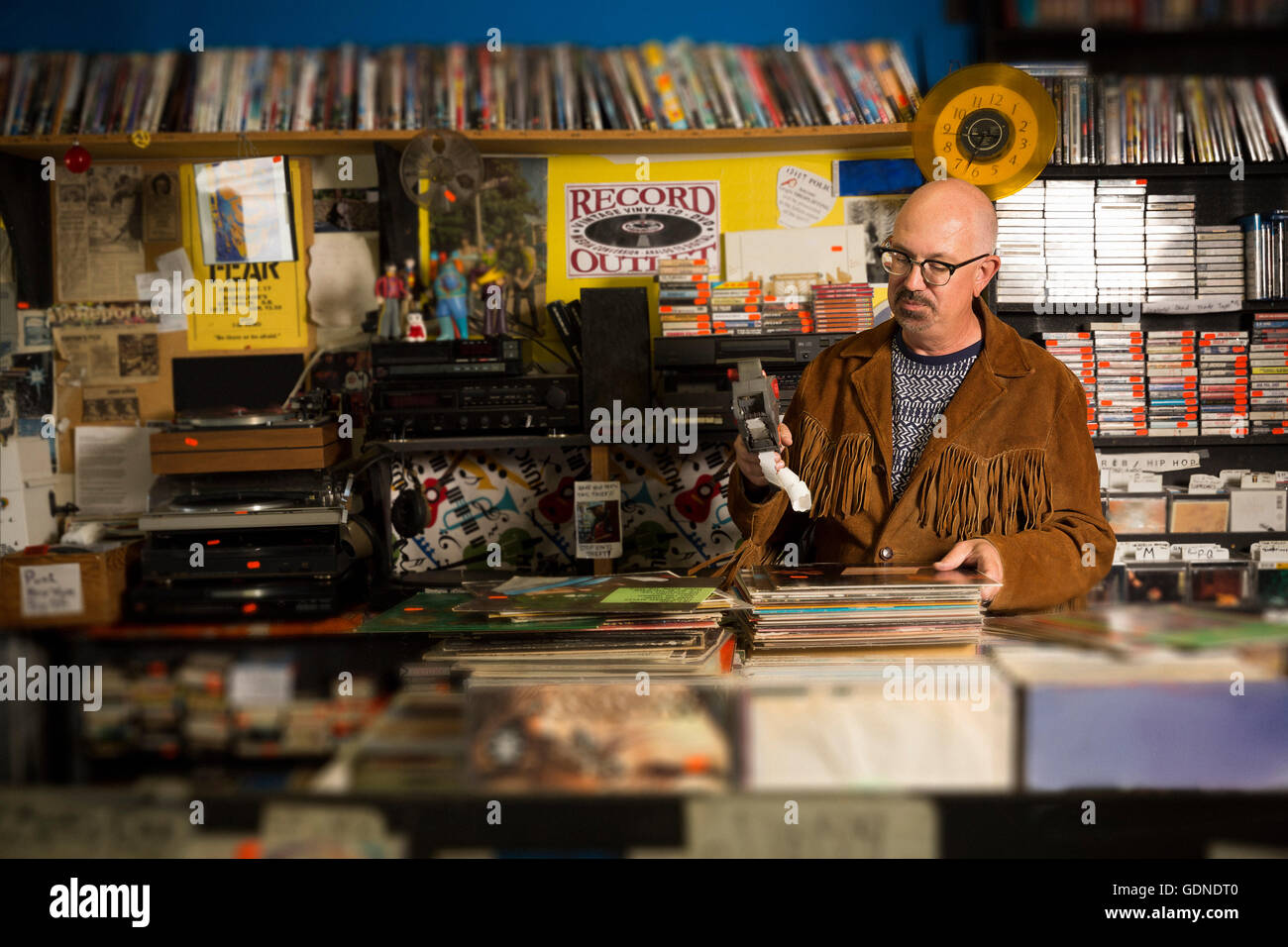 Mature man in record shop, pricing up records using price gun Stock Photo