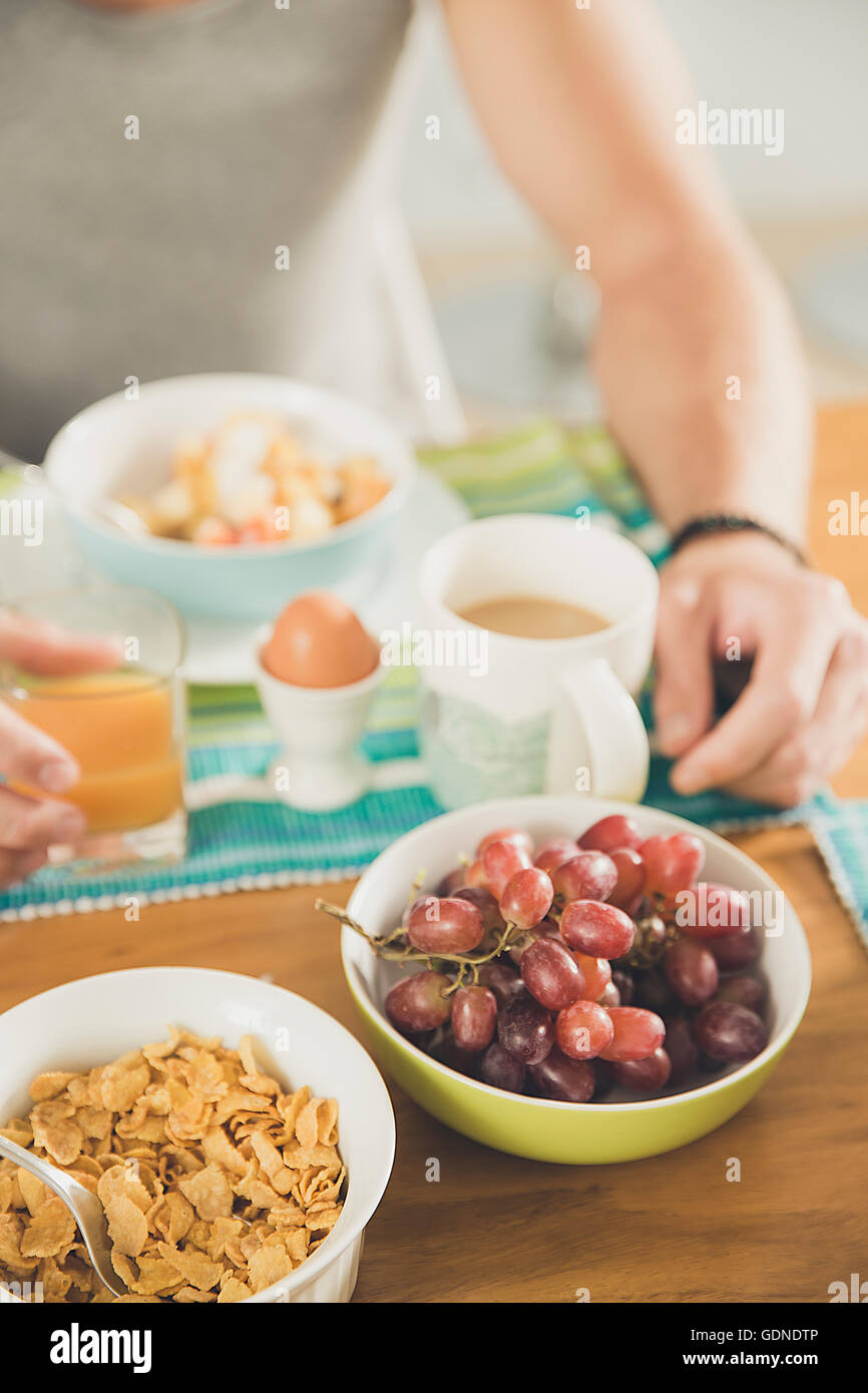 Cropped shot of young man at breakfast table of cereal, boiled egg and grapes Stock Photo
