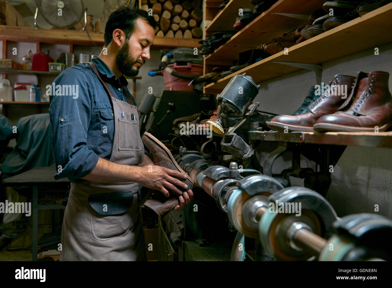 Male cobbler in traditional shoe workshop repairing boot Stock Photo