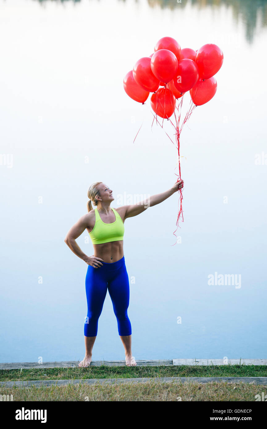 Woman holding bunch of red balloons Stock Photo