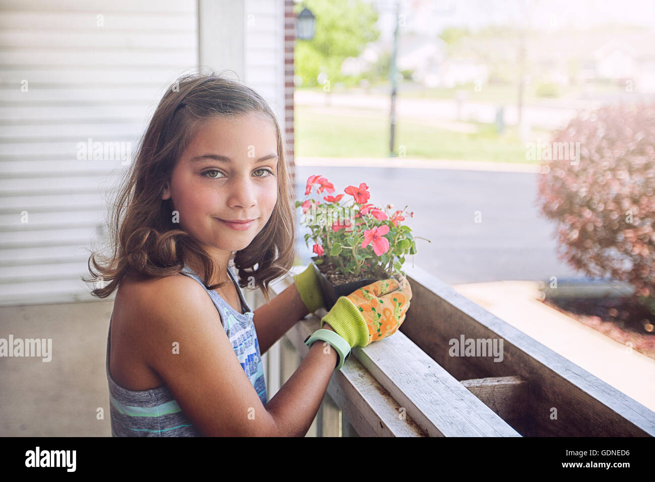Girl planting flowers in planter box, looking at camera smiling Stock ...