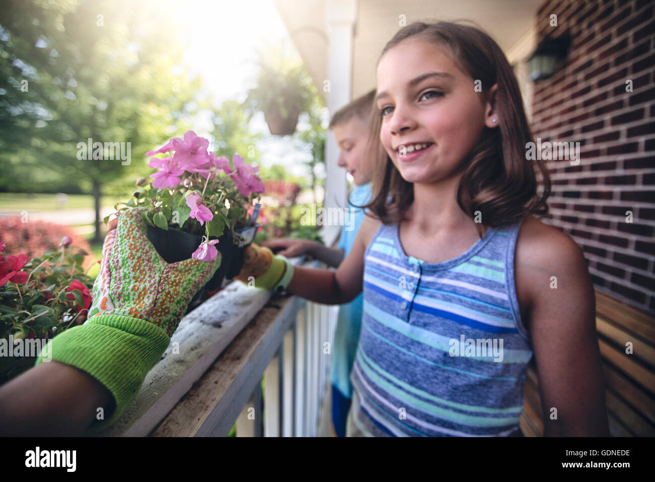 Hand wearing gardening glove handing plant to boy and girl Stock Photo