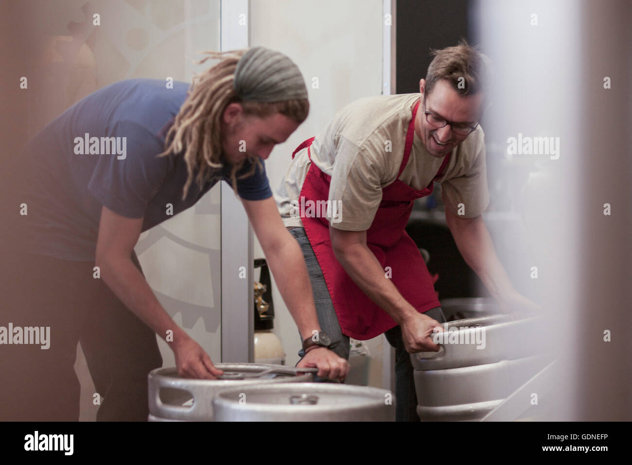 Colleagues in microbrewery moving beer kegs Stock Photo