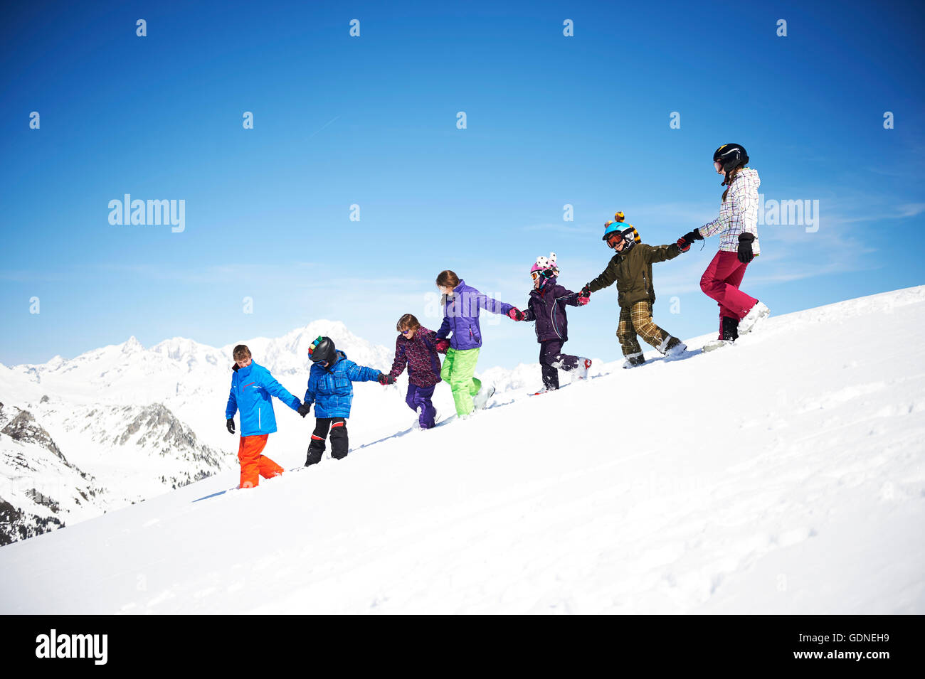 Group of children holding hands on snowy slope Stock Photo