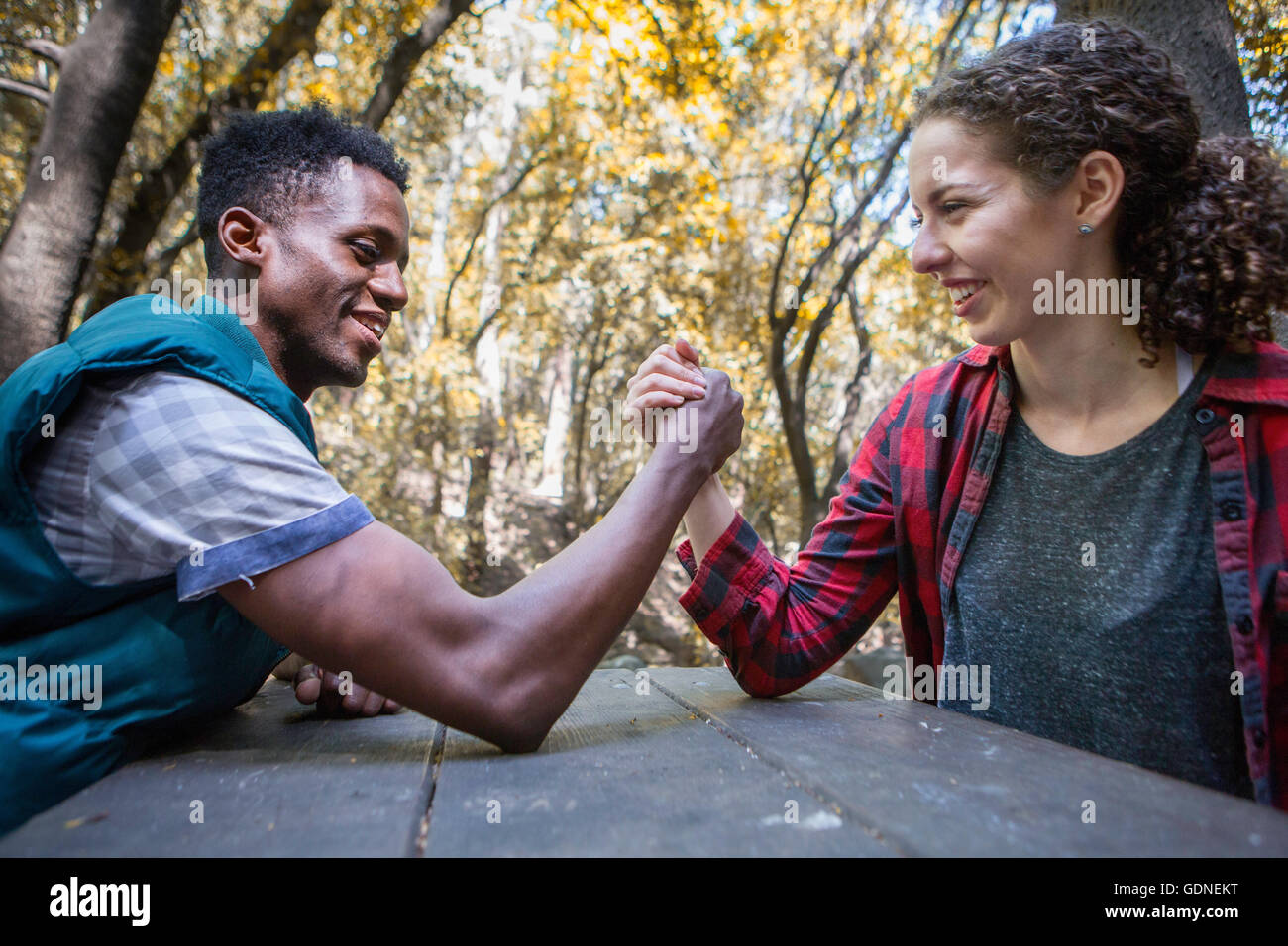 Young female hiker arm wrestling boyfriend at forest picnic table, Arcadia, California, USA