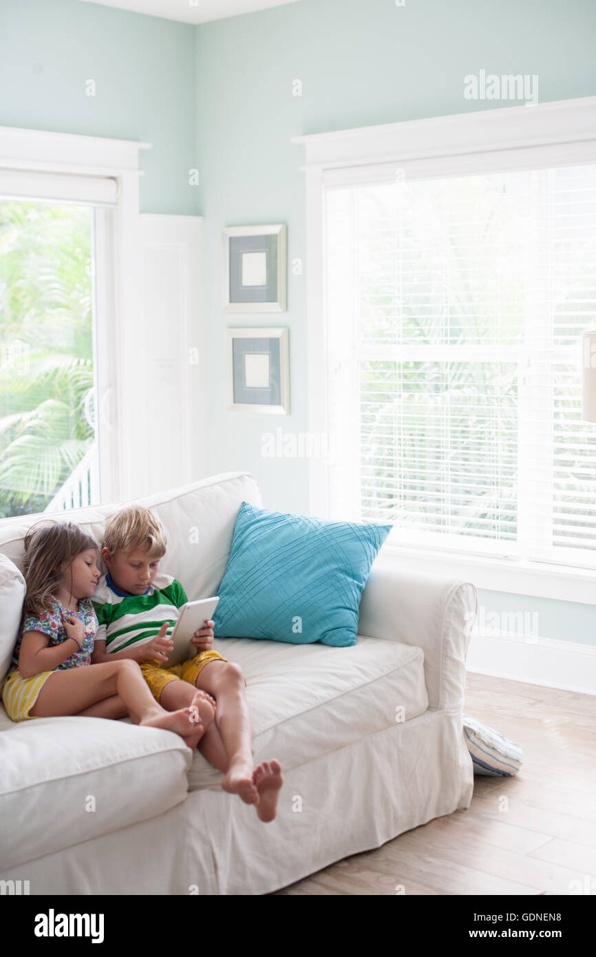 Brother and sister on sofa using digital tablet Stock Photo - Alamy