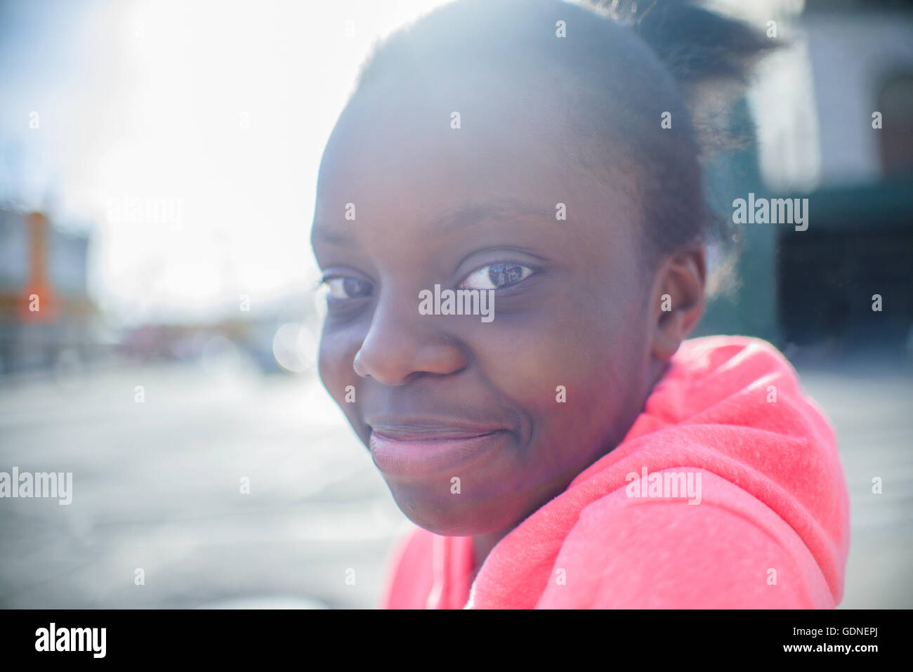 Portrait of teenage girl wearing pink hoody on urban sidewalk Stock Photo