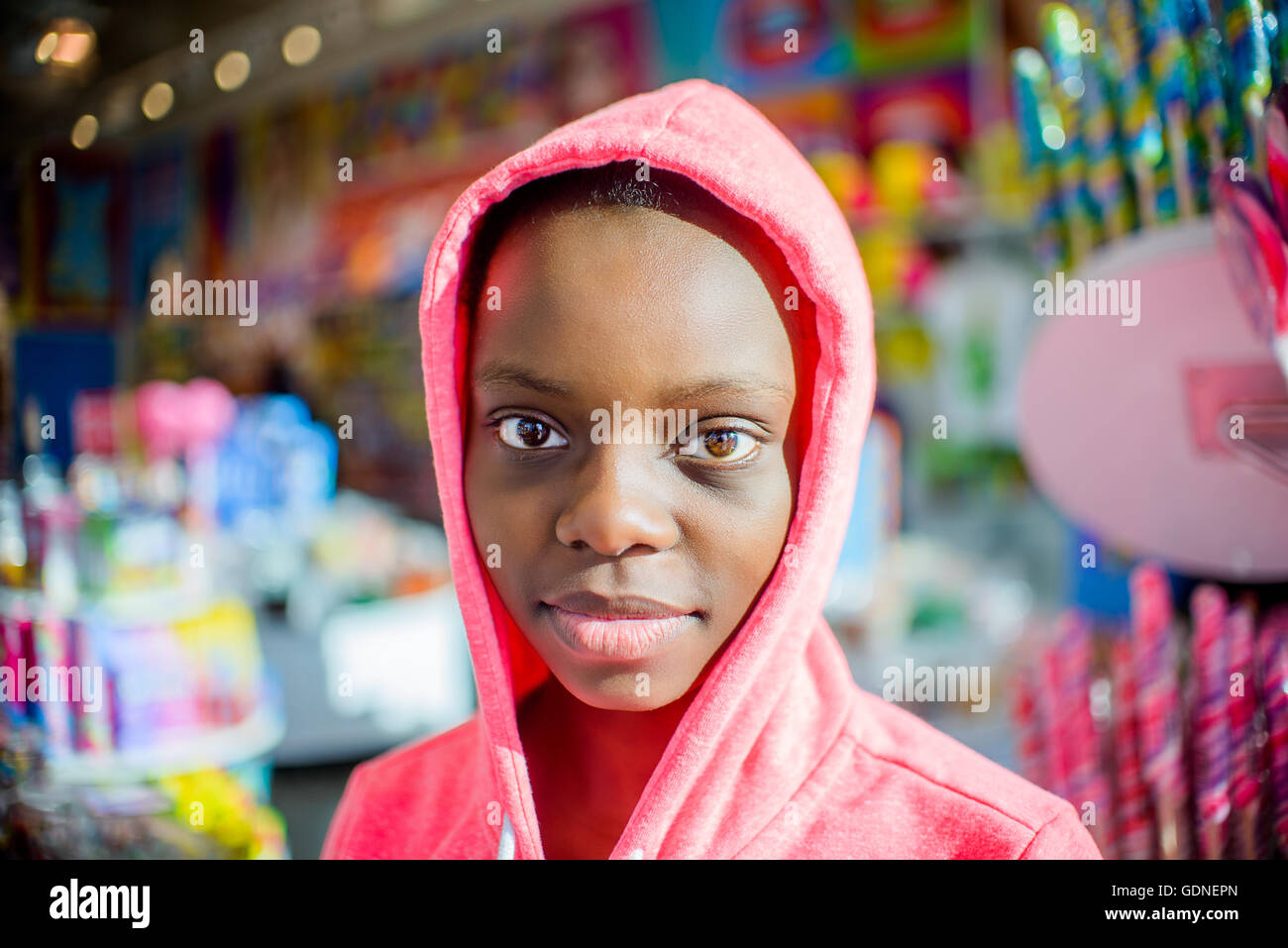 Portrait of teenage girl in front of candy stall wearing pink hoody, Brooklyn, USA Stock Photo