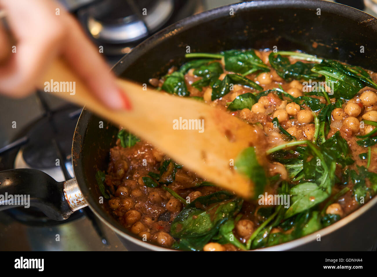 Cooking indian food with spinach, chickpeas, ginger and hot peppers