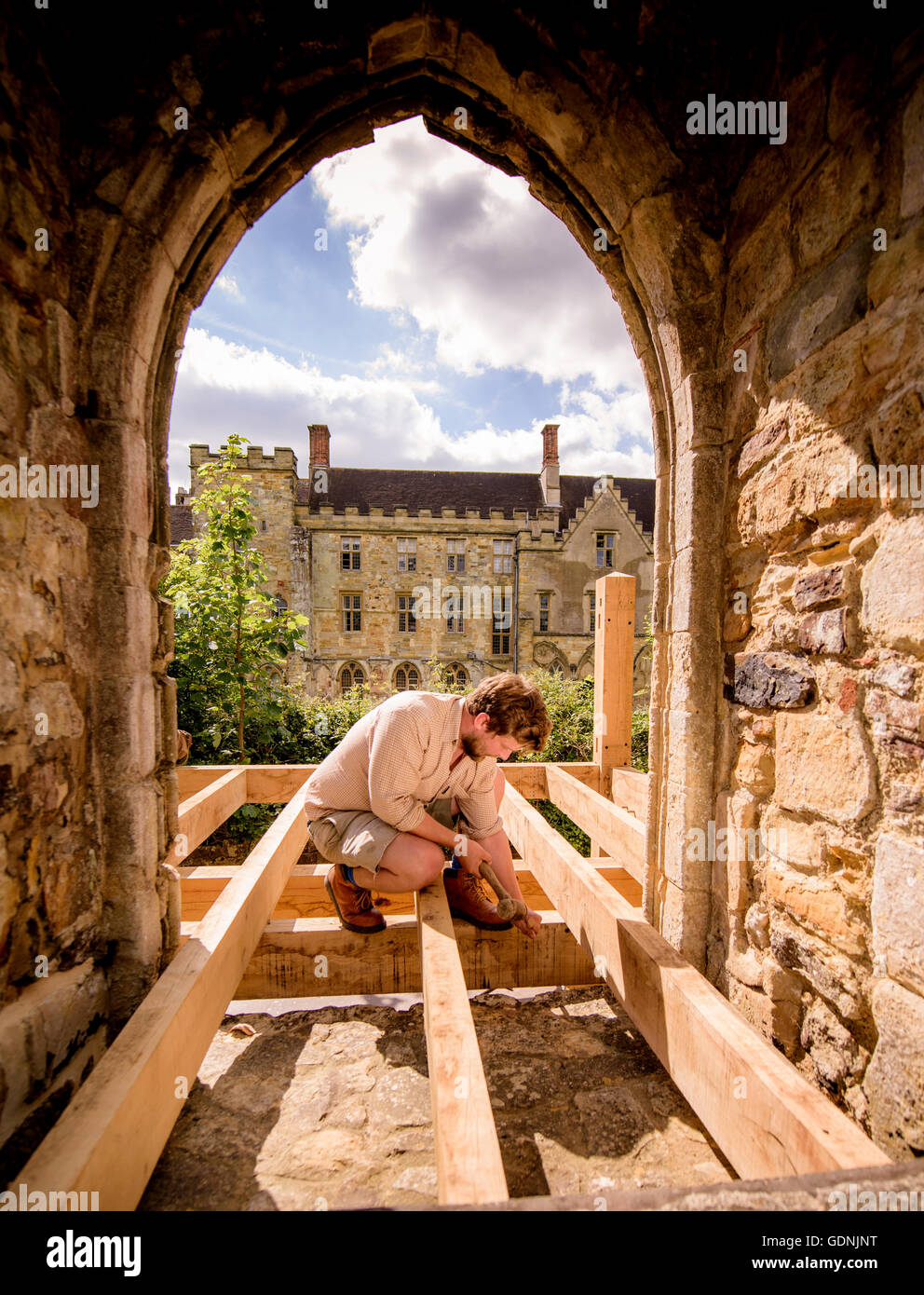Preparations for the 950th anniversary year of the Battle of Hastings near completion at Battle Abbey with English Heritage. A carpenter installs new oak-framed steps allowing visitor access to the dormitory range for the first time. Stock Photo