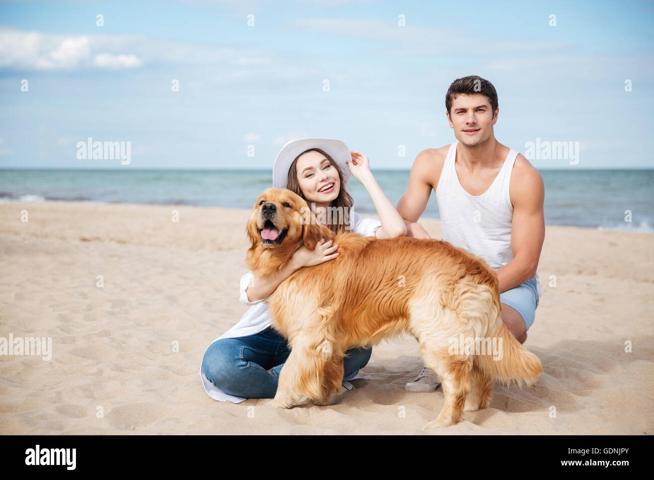 Beautiful young couple having fun with dog on the beach Stock Photo - Alamy
