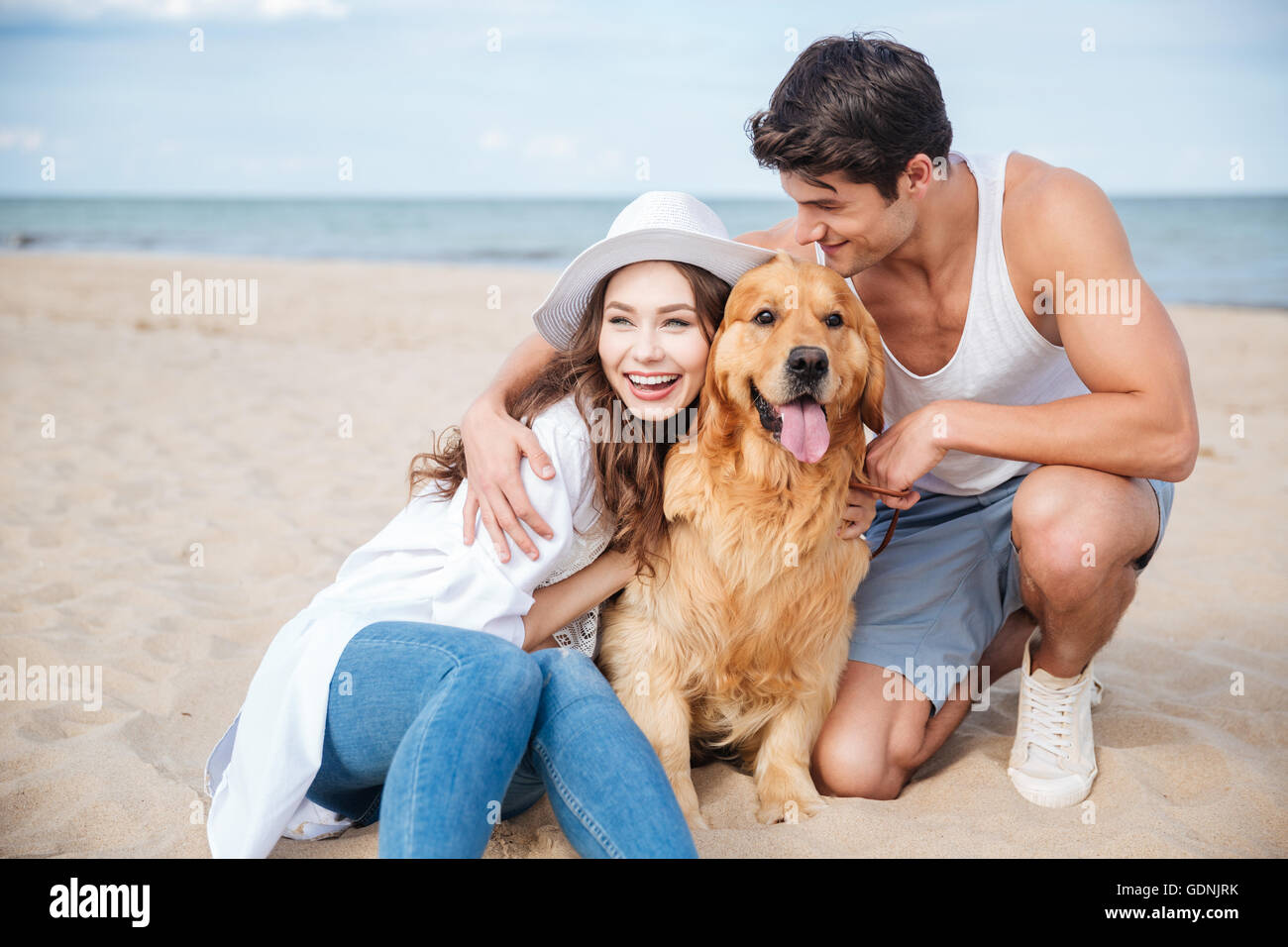 Young happy smiling couple in love sitting on the beach with dog Stock ...