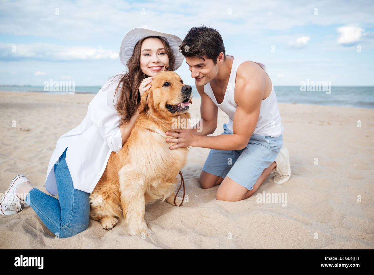Young happy smiling couple in love sitting on the beach with dog Stock ...