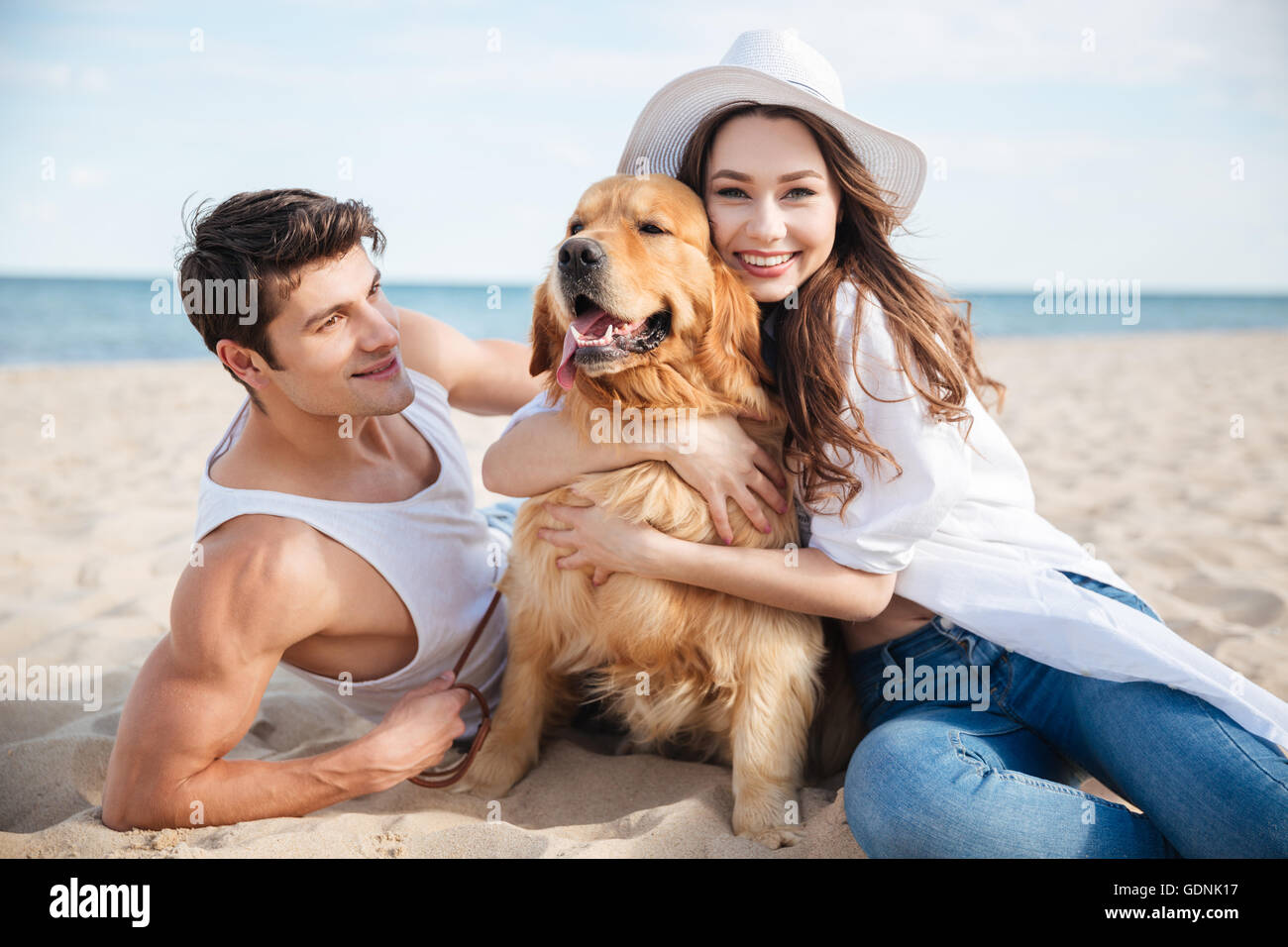 Young happy smiling couple in love sitting on the beach with dog Stock ...