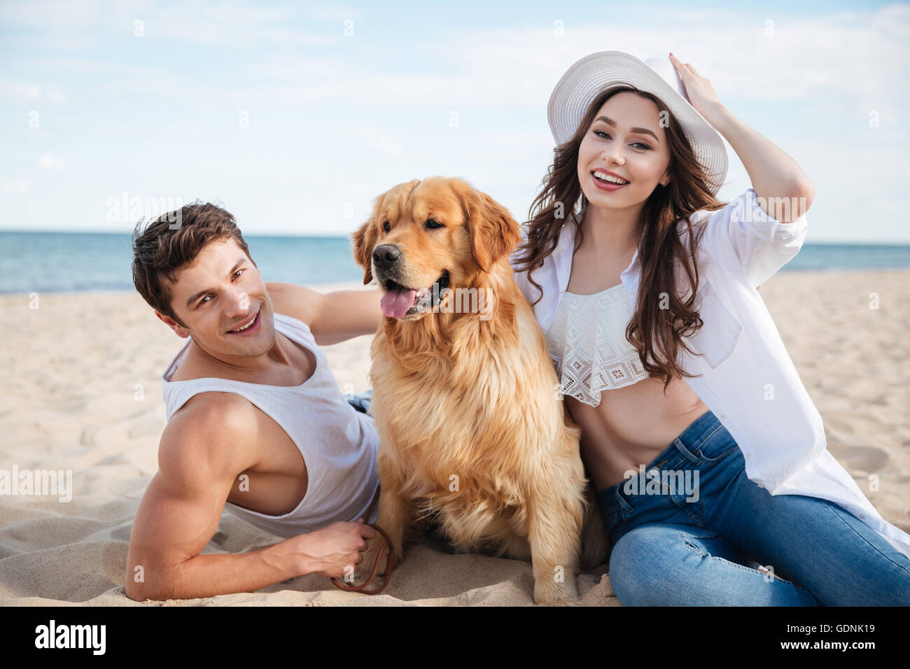 Young happy smiling couple in love sitting on the beach with dog Stock ...