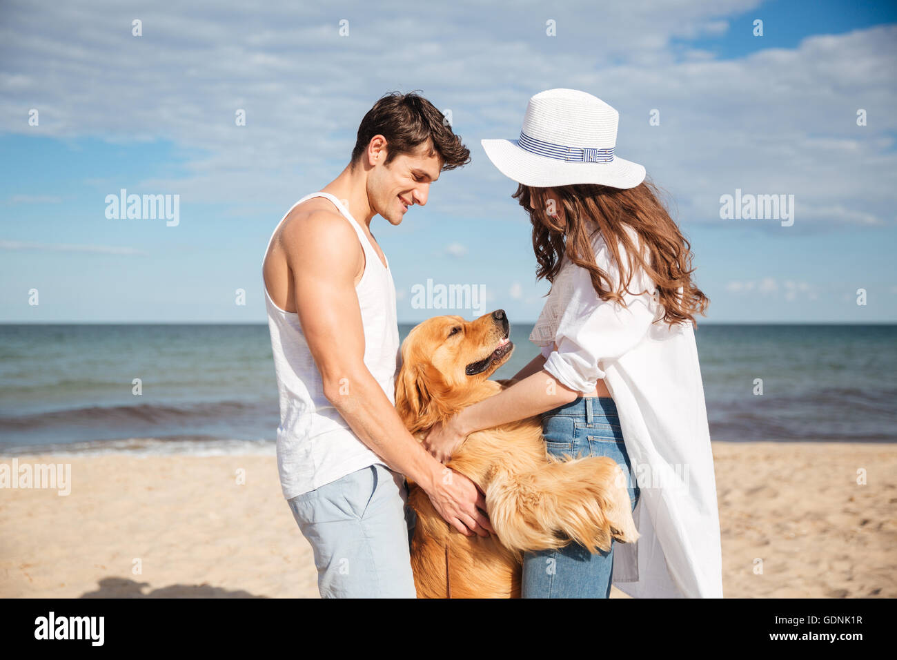 Young happy smiling couple in love sitting on the beach with dog Stock ...