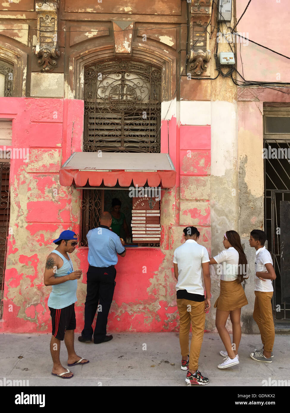 People including school children in uniform gather by a food kiosk in Havana Cuba Stock Photo