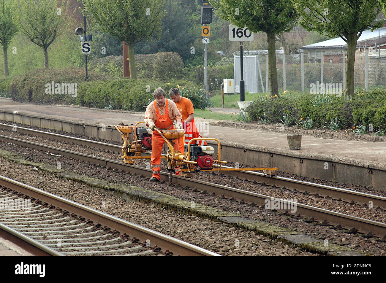 Railway workers in orange safety coats work on the track at a railway