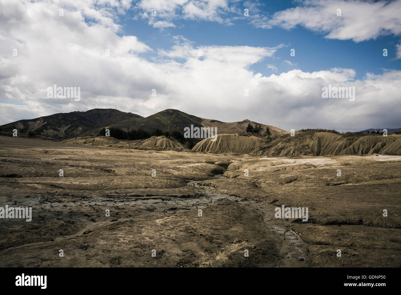 Dramatic Landscape shaped by mud volcanoes under partly cloudy sky Stock Photo