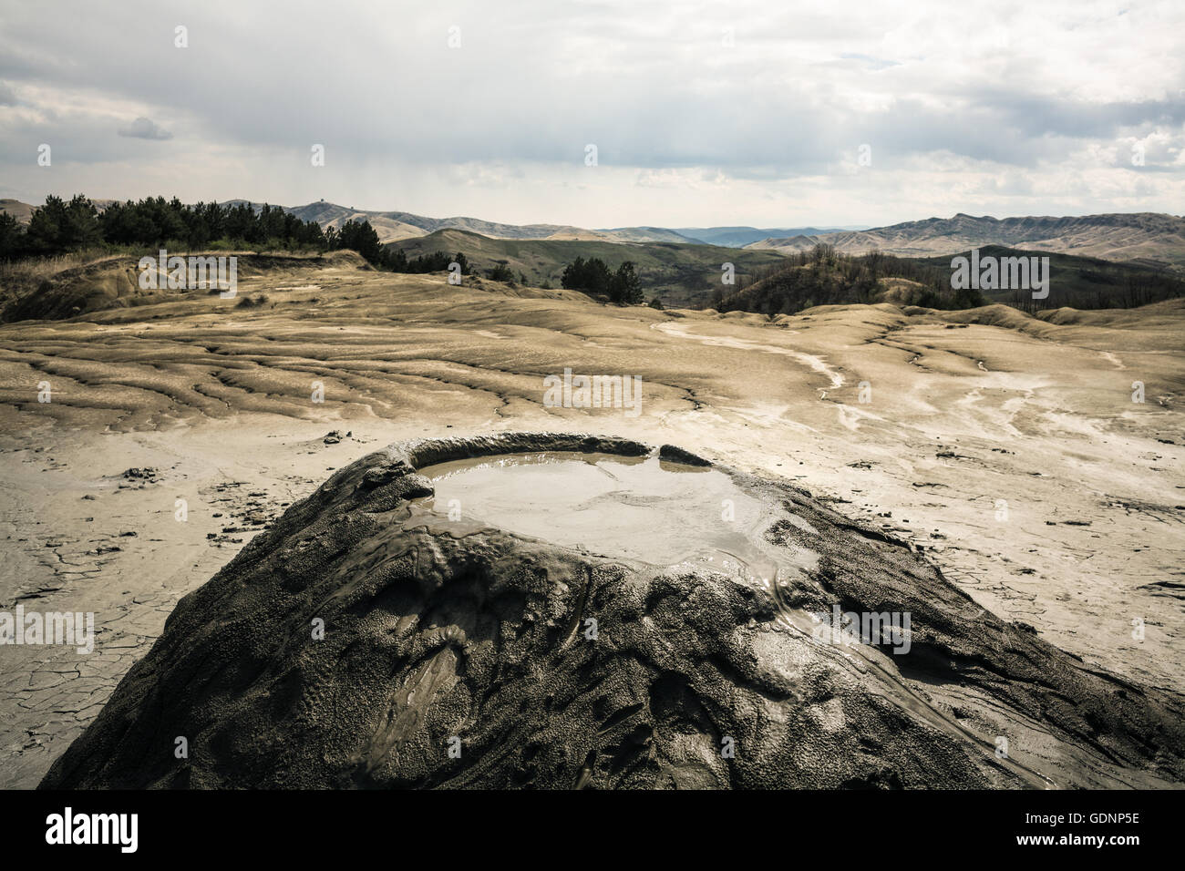 Active mud volcano under partly cloudy sky Stock Photo