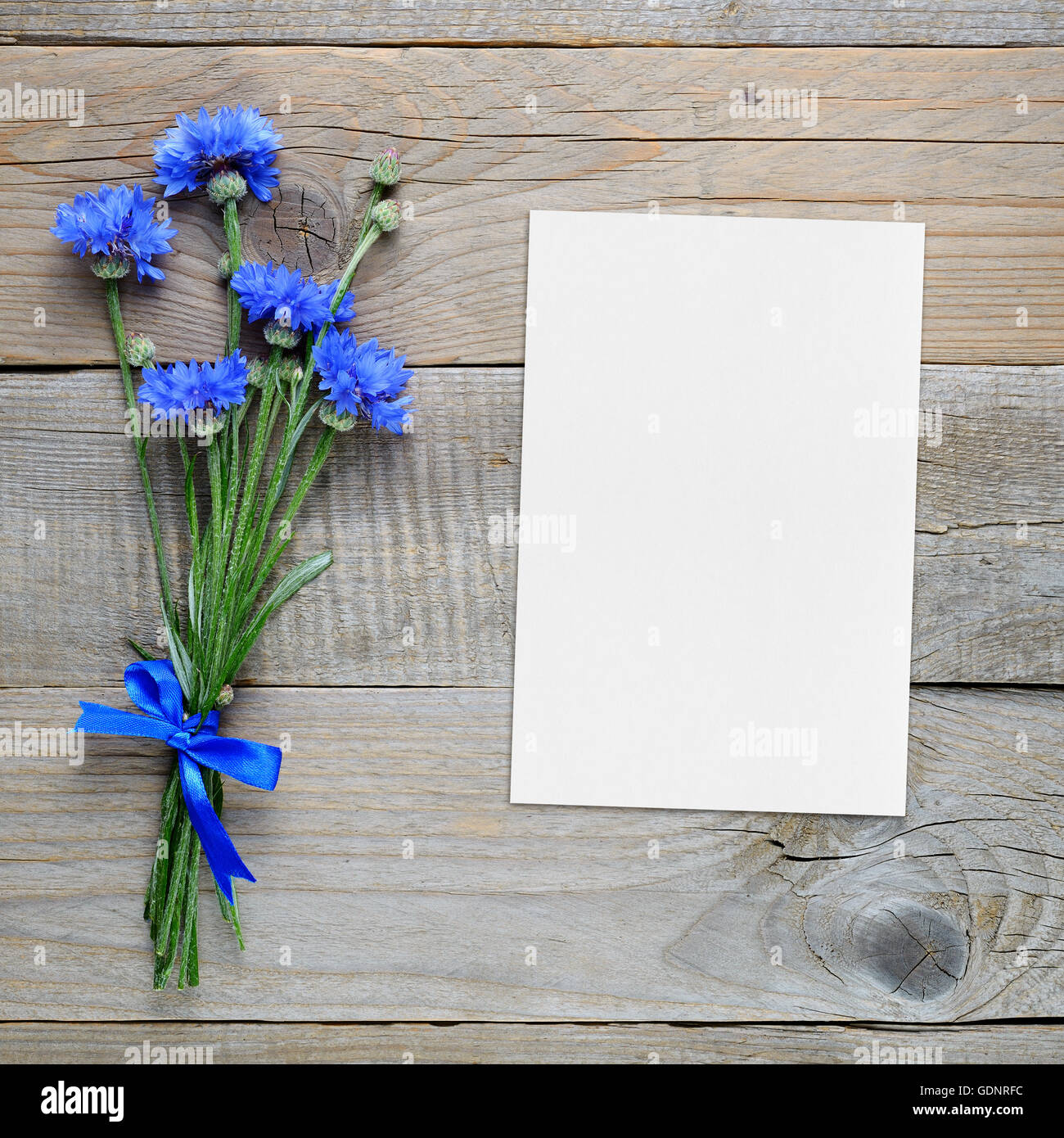 Bouquet of blue cornflowers and blank greeting card on wooden background Stock Photo