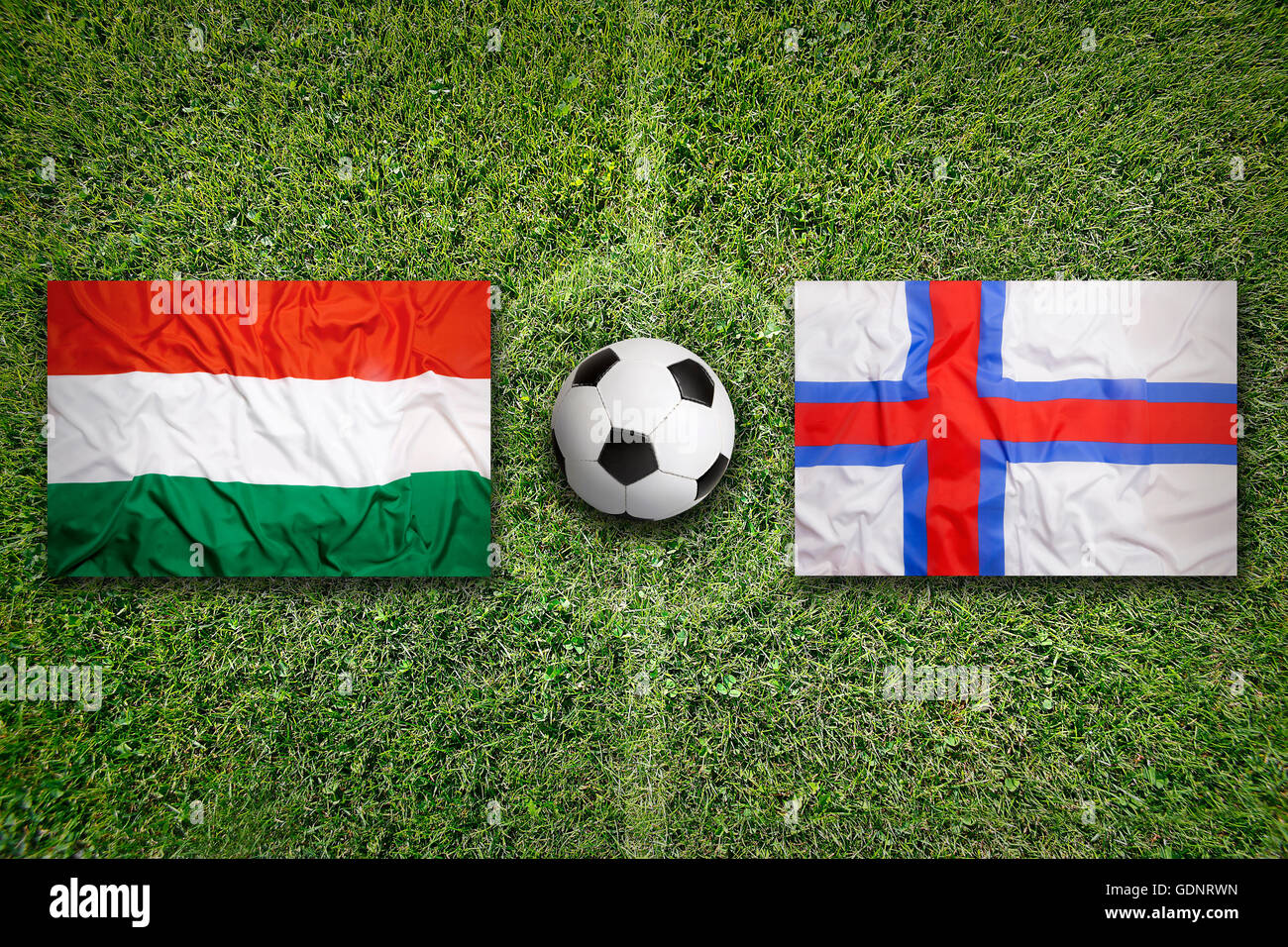 Hungary vs. Faeroe Islands flags on green soccer field Stock Photo
