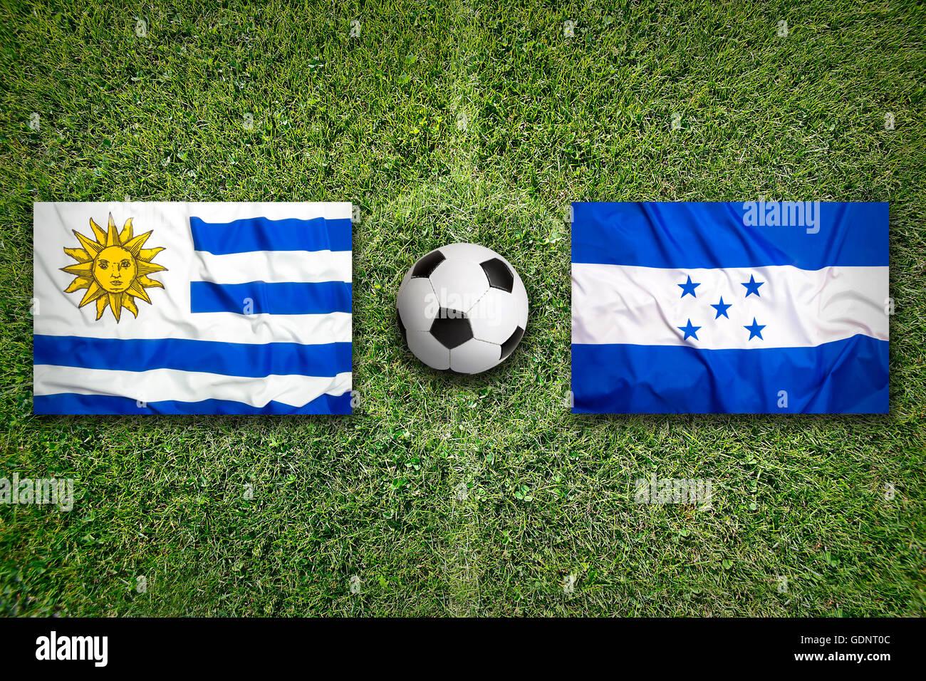 Uruguay vs. Honduras flags on green soccer field Stock Photo