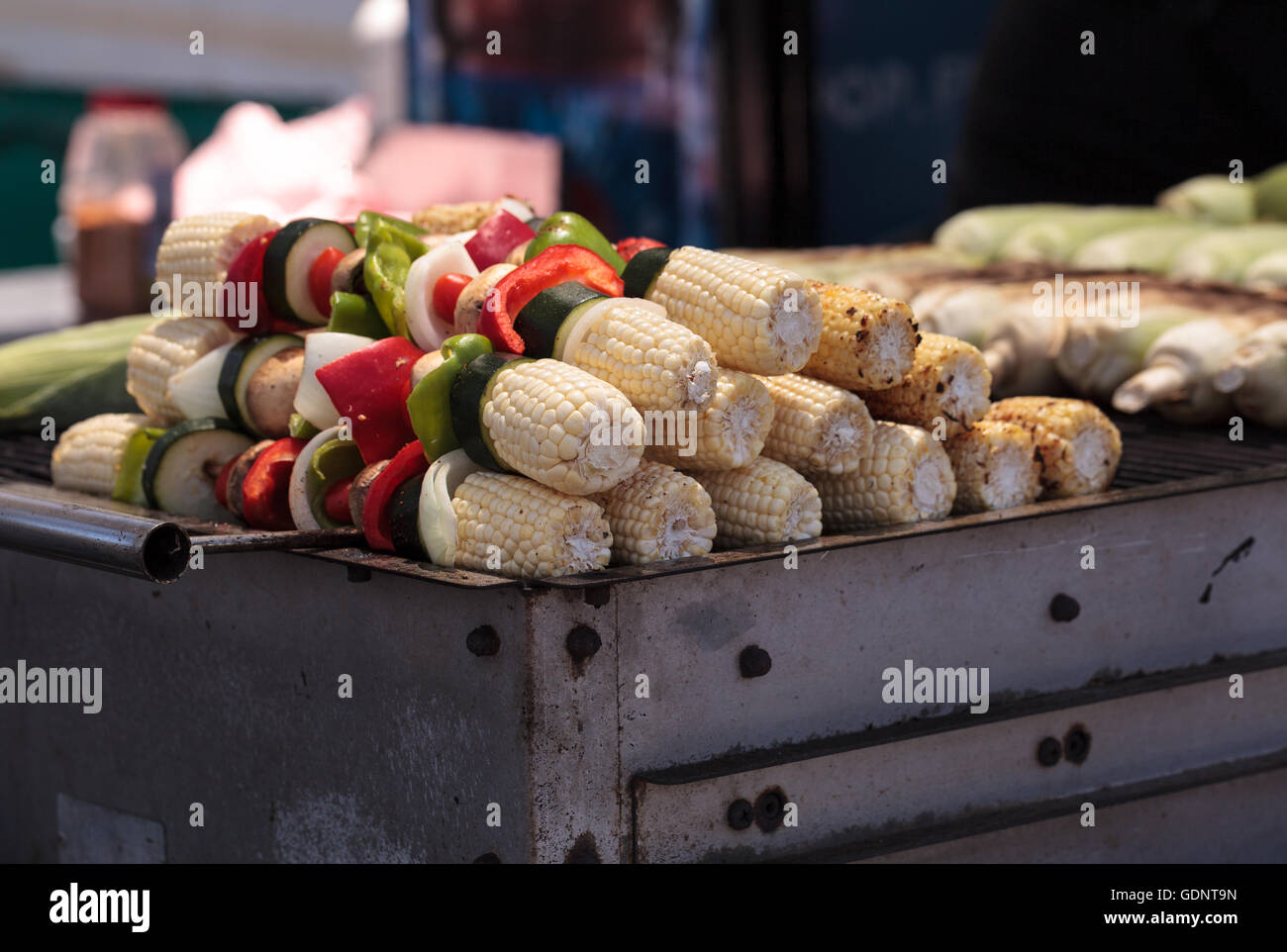 Corn, pepper and onion kabobs on a barbecue grill cooking at a fair
