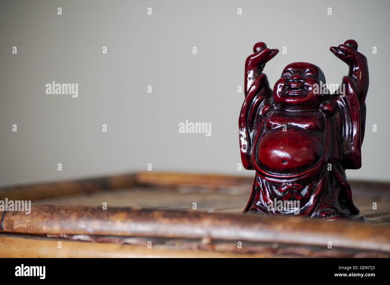 Happy red Buddha figurine on bamboo Stock Photo
